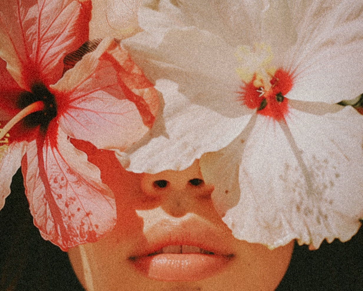 Person with flowers covering their face against a blurred background