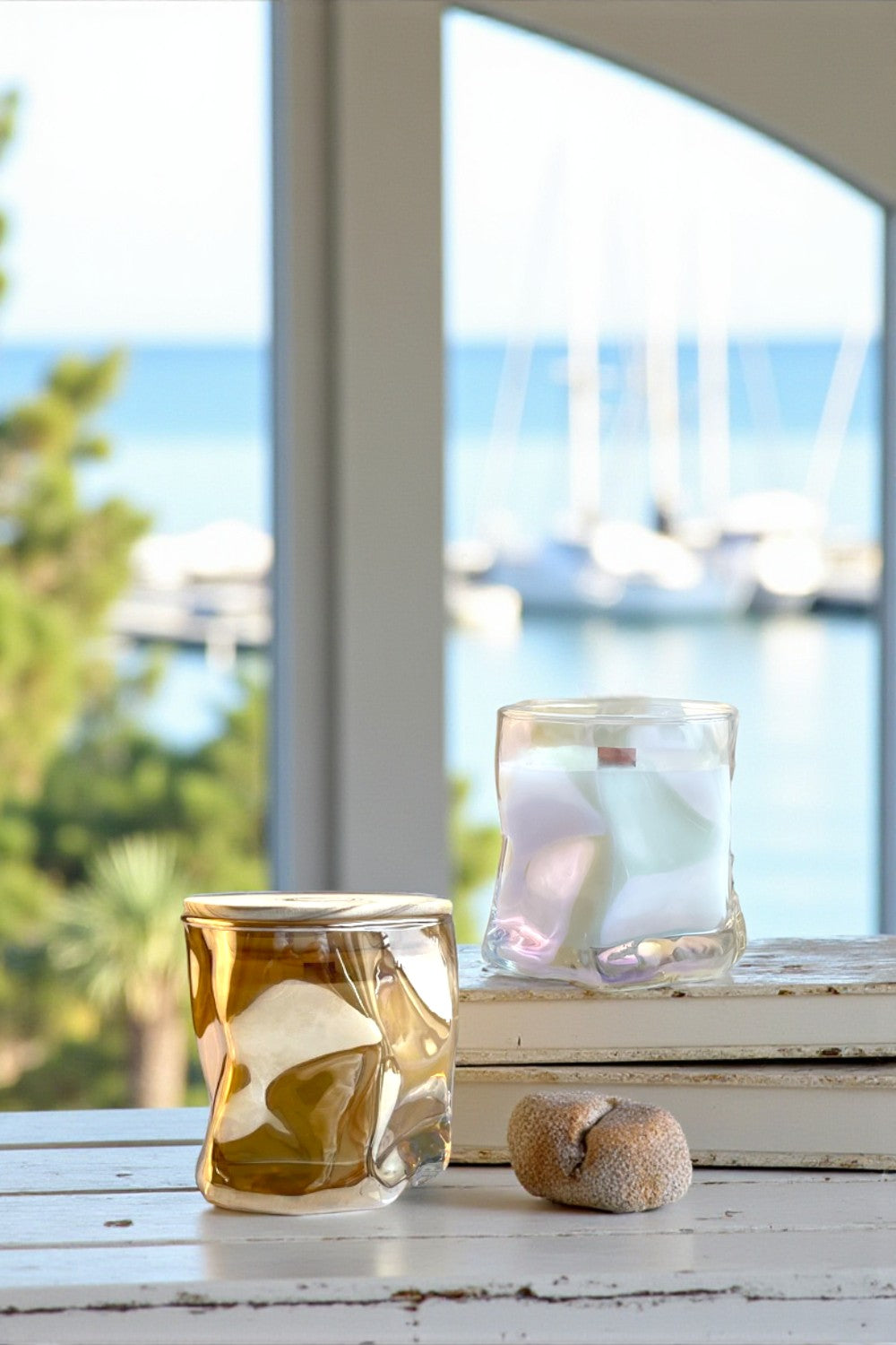 Two glass containers with marbled designs on a surface with a blurred outdoor background