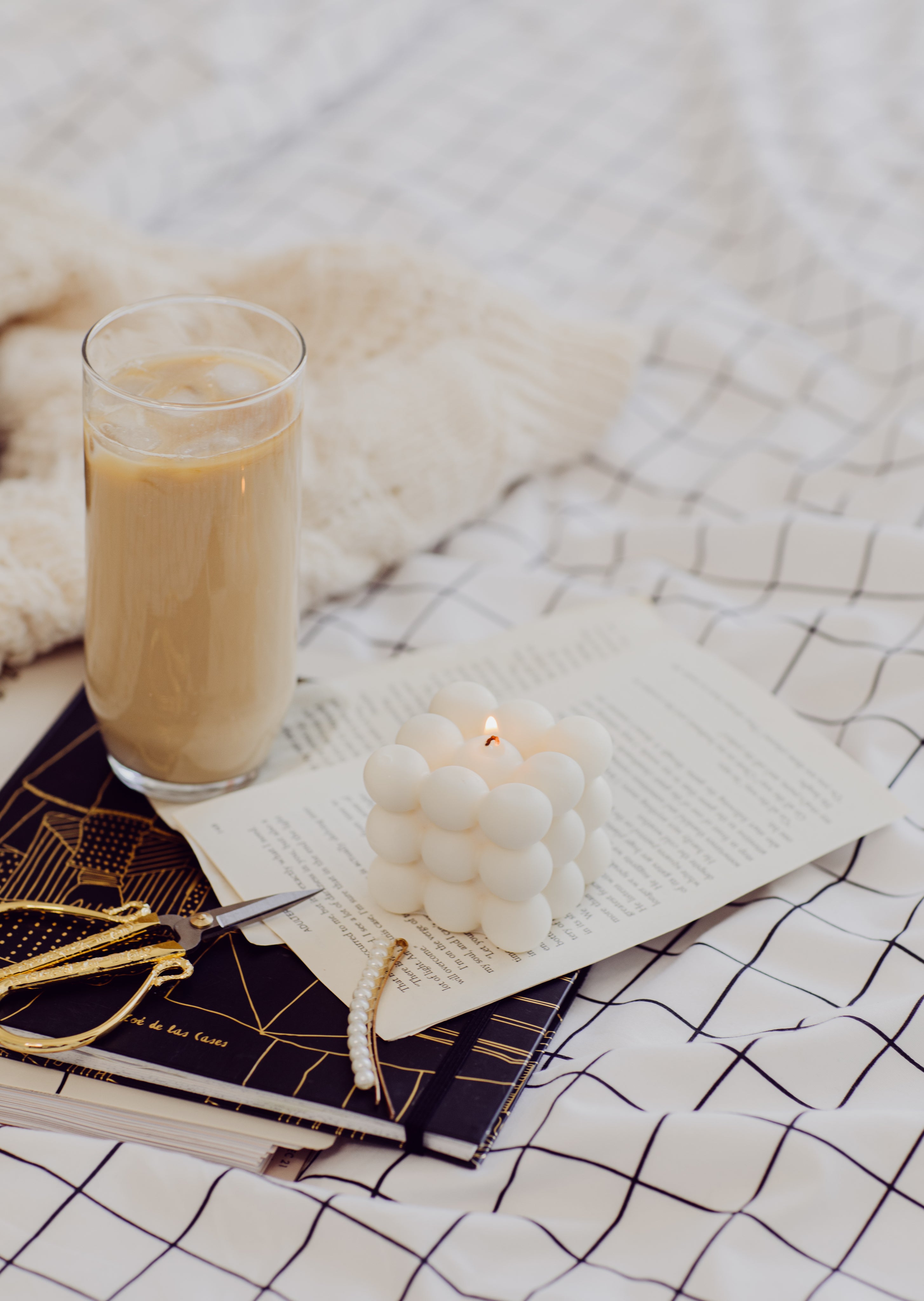 a-lit-candle-with-iced-coffee-and-hair-accessories